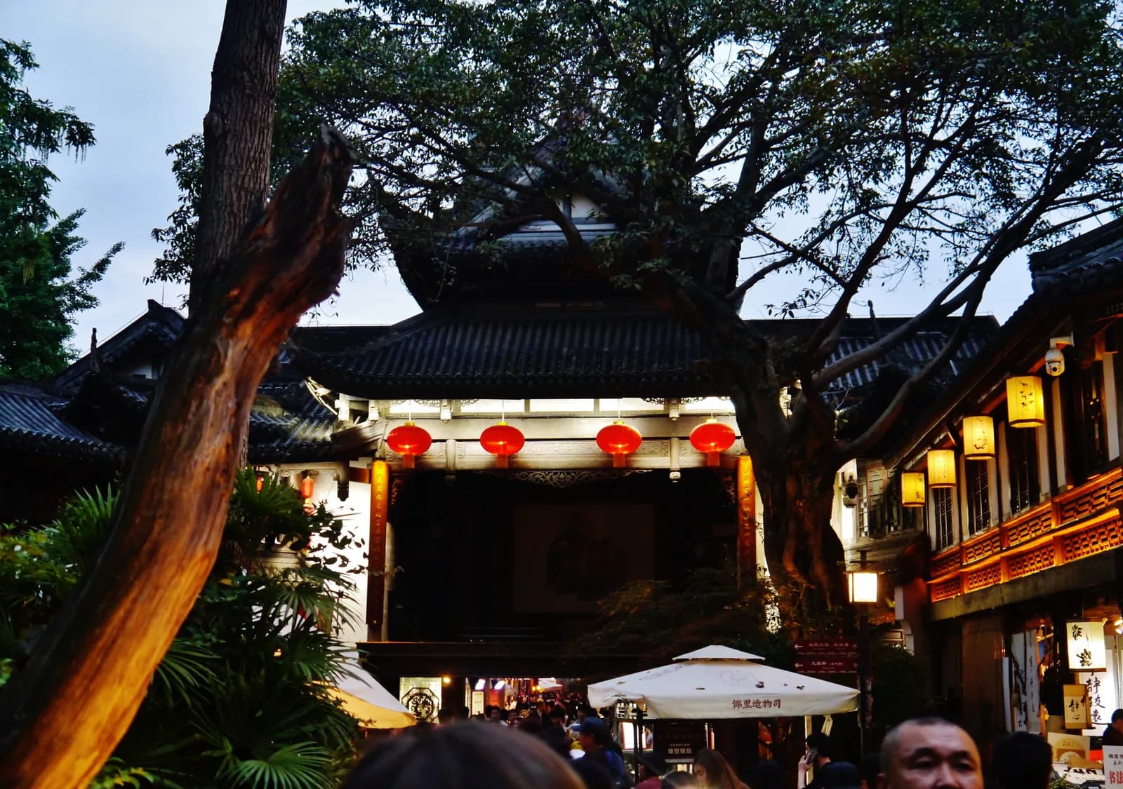 Crowds walking the lantern-lined Jinli heritage street in Chengdu beside grey timber shopfronts
