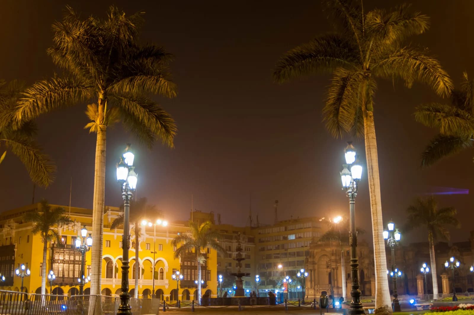 The Plaza Mayor of Lima with its central fountain, colonial facades and the cathedral under a grey coastal sky