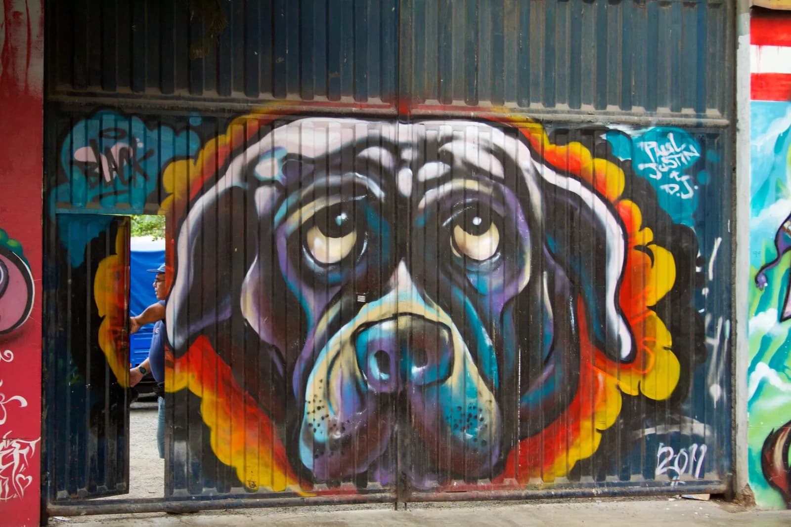 A large colorful street art mural on a wall in Barranco, Lima, with pedestrians passing in front