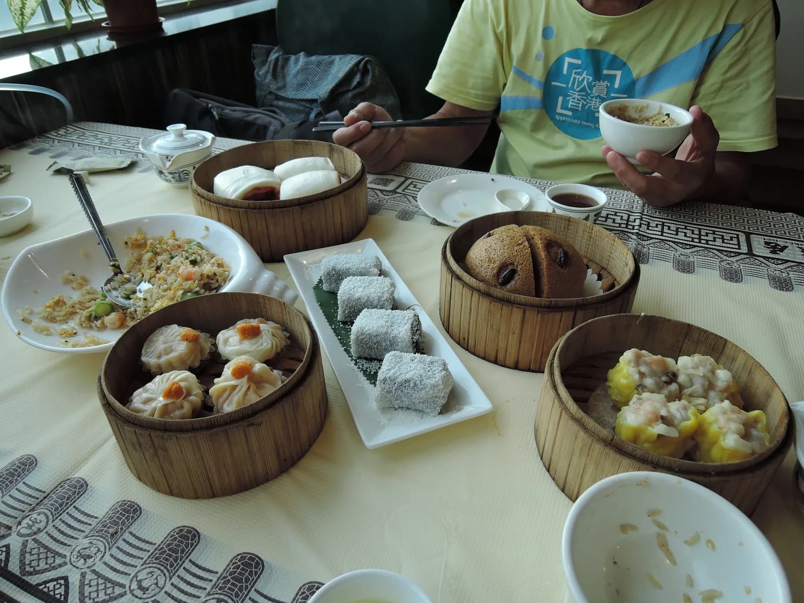 A table crowded with bamboo steamers and plates of Cantonese dim sum dishes